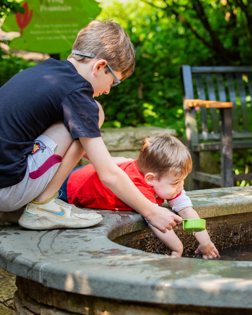 Two small boys play in the frog fountain at the Morton Arboretum